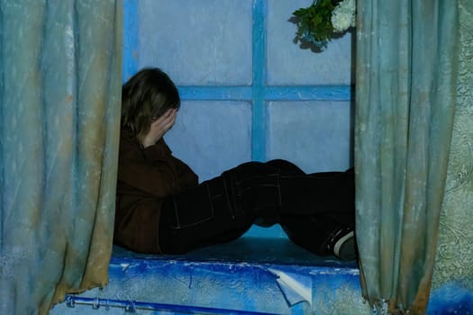 Sad girl in a state of sadness and depression on the windowsill in a state of loneliness and depression