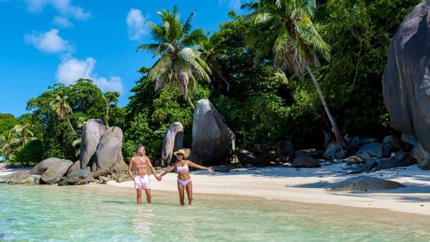 Mahe Seychelles tropical island with white sandy beaches and palm trees, a couple of men and women mid age on vacation at Seychelles visiting a tropical beach