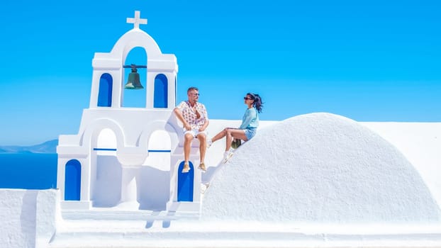 A couple watching the sunset on vacation in Santorini Greece, men and women visit the Greek village of Oia Santorini.