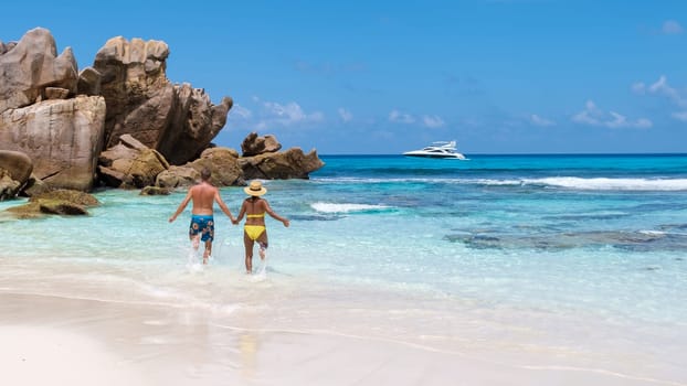 Anse Cocos Beach La Digue Island Seychelles, a happy couple of men and woman walking at the beach at a luxury vacation in the Seychelles, men and woman jumping in sky happiness on vacation