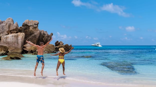 Anse Cocos Beach La Digue Island Seychelles, a happy couple of men and woman at the beach at a luxury vacation in the Seychelles, men and woman jumping in the sky happy on vacation