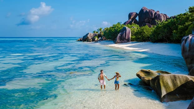 Anse Source d'Argent beach La Digue Island Seychelles, a couple of men and woman walking at the beach at a luxury vacation.