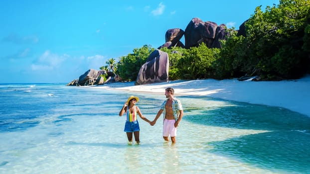 Anse Source d'Argent beach La Digue Island Seychelles, a couple of men and women walking at the beach at a luxury vacation. a couple swimming in the turqouse colored ocean of La Digue