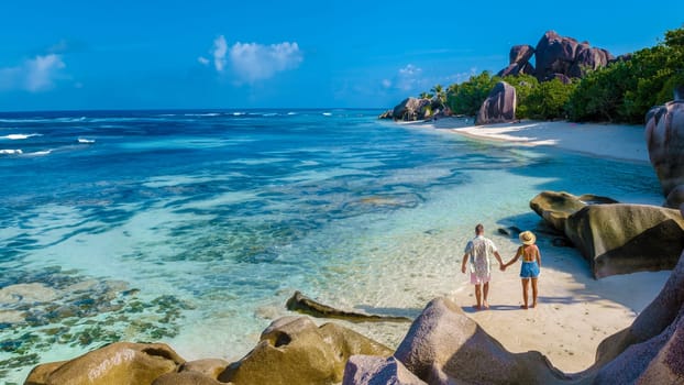 Anse Source d'Argent beach La Digue Island Seychelles, a couple of men and woman walking at the beach at a luxury vacation. a couple swimming in the turqouse colored ocean on a sunny day