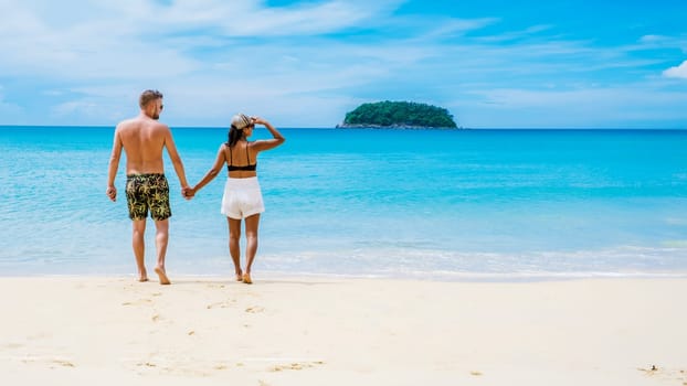 couple walking on the beach of Kata Phuket Thailand during vacation, happy men and woman on vacation holidays in Thailand walking by the ocean of Kata Beach Phuket