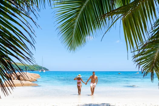 a mature couple of men and women on vacation in Seychelles visiting the tropical beach of Anse Lazio Praslin Seychelles. couple walking at a tropical beach