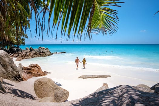 Anse Source d'Argent beach La Digue Island Seychelles, a couple of men and women walking at the beach at a luxury vacation. a couple swimming in the turqouse colored ocean during summer holidays