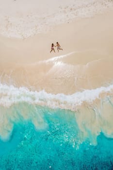 Man and woman lying down on a tropical beach, Drone view from above at a tropical beach in the Seychelles Cocos Island, view from above at a tropical beach, couple on vacation