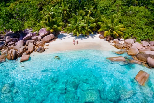 Praslin Seychelles tropical island with white beaches and palm trees, a couple of men and women mid age on vacation at Seychelles visiting the tropical beach Anse Lazio Praslin Seychelles