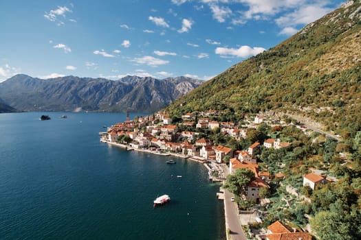 Boat is moored in the bay near the winding shore of Perast with a view of the bell tower. Montenegro. Drone. High quality photo