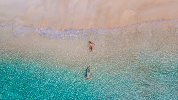 drone view of a men and woman swimming in the blue turqouse colored ocean of Koh Kradan island in Thailand. top view from above at the beach of Koh Kradan Trat Thailand