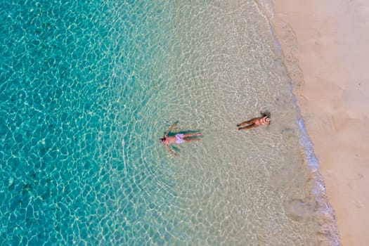 drone view of a man and woman swimming in the blue turqouse colored ocean of Koh Kradan island in Thailand. top view from above at the beach of Koh Kradan Trat Thailand