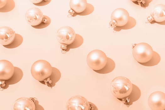 Color of the year 2024: Peach Fuzz. beige shiny christmas balls on beige pastel background, pattern. Winter, Cristmas and New year concept. Top view, flat lay