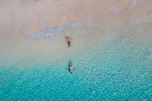drone view from above of a man and woman swimming in the blue turqouse colored ocean of Koh Kradan island in Thailand. top view from above at the beach of Koh Kradan Trat Thailand