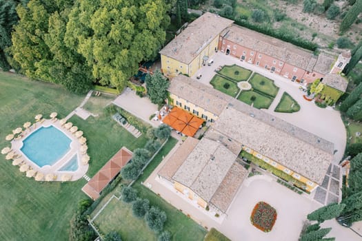 Swimming pool with sun umbrellas in the garden near the ancient Villa Cordevigo. Verona, Italy. Drone. High quality photo