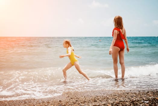 Happy loving family mother and daughter having fun together on the beach. Mum playing with her kid in holiday vacation next to the ocean - Family lifestyle and love concept.