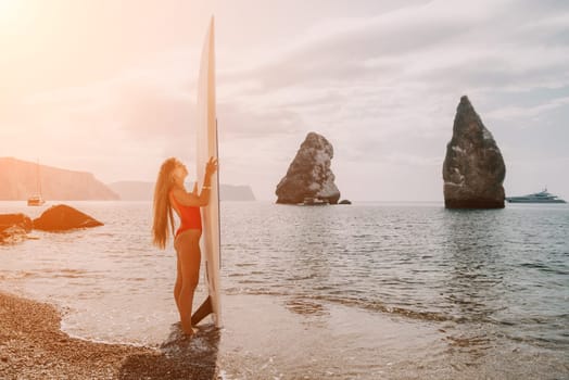 Close up shot of beautiful young caucasian woman with black hair and freckles looking at camera and smiling. Cute woman portrait in a pink bikini posing on a volcanic rock high above the sea