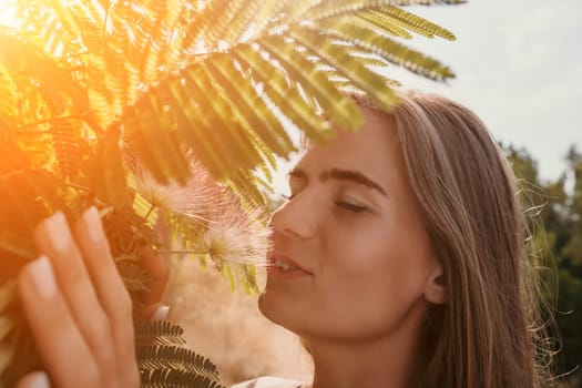 Beauty portrait of young woman closeup. Young girl smelling Chinese acacia pink blossoming flowers. Portrait of young woman in blooming spring, summer garden. Romantic vibe. Female and nature.