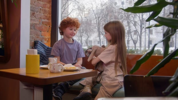 Cute couple of kids in cafe. Stock footage. Beautiful couple of kids on date in cafe. First love of children on date in cafe.