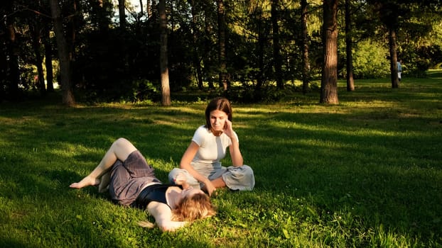 Rest in a quiet place. Concept. Two friends in summer clothes relaxing in a green clearing under the sun. High quality 4k footage