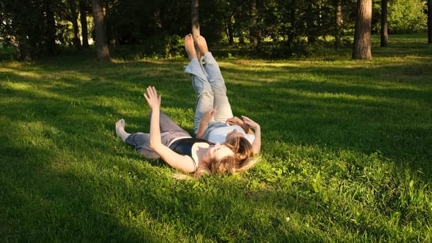 Friends are lying on green grass in park on sunny summer day. Concept. Beautiful girlfriends are lying on green grass in park. Relaxing in park on grass.