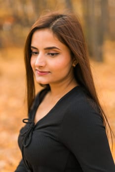 Close up portrait of pretty indian young woman enjoying warm autumn sunny day vacation outdoors. Generation z and gen z concept. Fall Season.