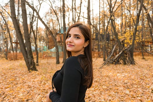 Close-up portrait of a young beautiful confident Indian Asian woman in fall outdoor. Happy and natural smiling female. Generation z and gen z youth