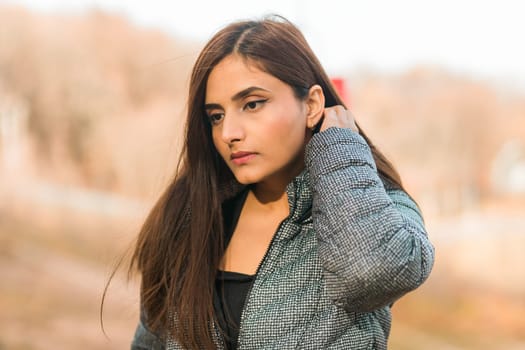 Close up portrait of pretty indian young woman enjoying warm autumn sunny day vacation outdoors. Generation z and gen z concept. Fall Season.