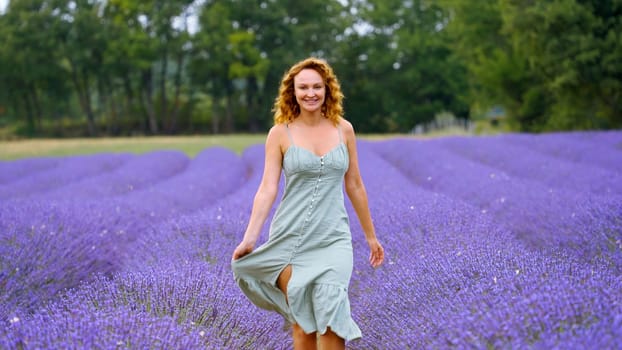 Young woman in a blue dress walking through lavender field. Action. Beautiful girl in Provence, France