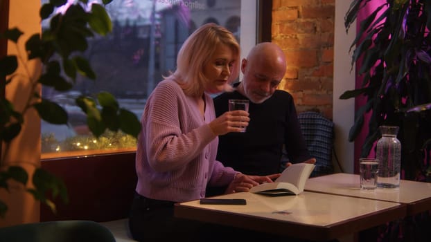 Elderly couple on date in restaurant. Stock footage. Beautiful elderly couple is having nice time on date. Elderly couple on date at restaurant in evening.