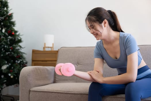 Young Asian woman exercise with dumbbells at home.