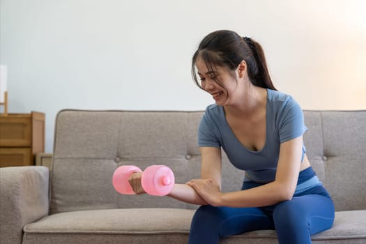 Young Asian woman exercise with dumbbells at home.