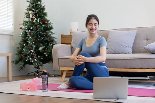 Young Asian sporty fitness woman coach do practice video online training yoga laptop in living room at home.