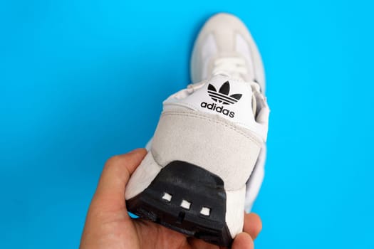 Tyumen, Russia-October 03, 2023: White adidas sneakers on blue background. New clean sneakers
