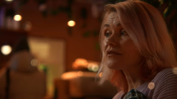 Woman is cold and taking a blanket at the restaurant on a date. Stock footage. Senior woman getting warm at a cafe in the evening
