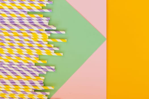 Drinking paper straws on yellow background with copy space. Top view of colored paper disposable eco-friendly straws for summer cocktails.