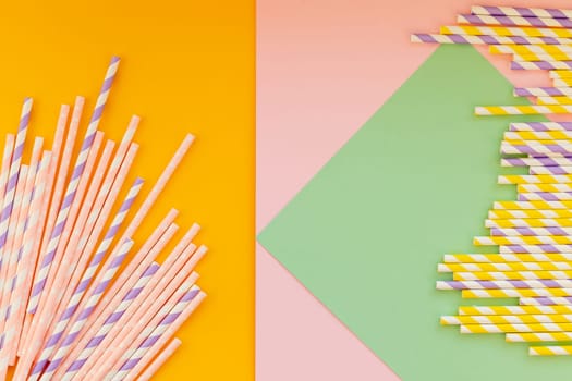 Drinking paper straws on yellow background with copy space. Top view of colored paper disposable eco-friendly straws for summer cocktails.