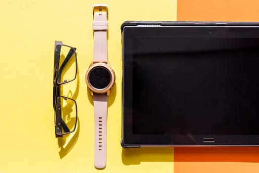 Flat lay feminine workspace with tablet, notebook, smart phone, hand wrist watch and computer mouse. Stylish female office table, top view