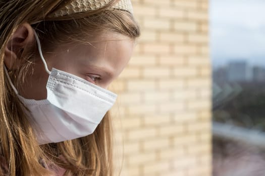 Coronovirus Quarantine Concept.A girl with a toy in a protective mask from the virus on her face