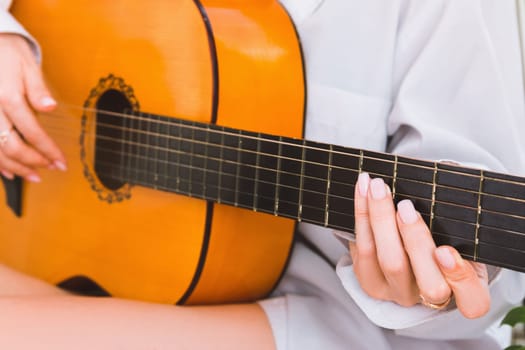 A woman in a white shirt plays the guitar, close-up