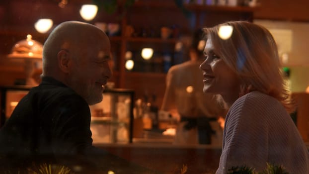Side view of senior man and woman sitting at table with Christmas decoration. Stock footage. Happy husband and wife together at the restaurant