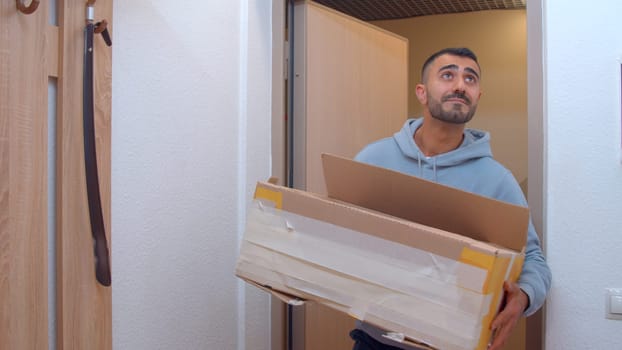 The courier brought the package. Media. An adult handsome man in oversize clothes brought boxes to a new apartment. High quality 4k footage