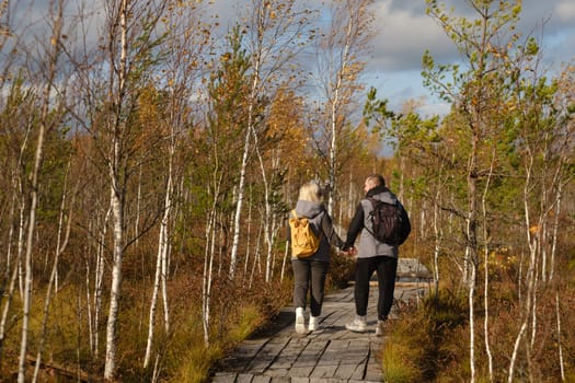 Two tourists walk along a wooden path in a swamp in Yelnya, Belarus.