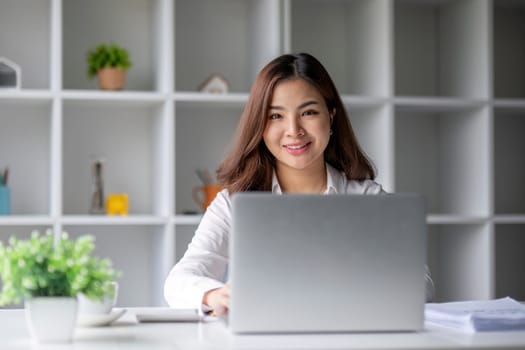 Young beautiful business woman using laptop and checking documents while working on laptop.