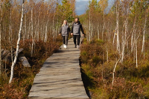 Two tourists walk along a wooden path in a swamp in Yelnya, Belarus.