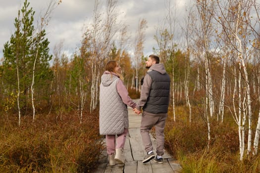 Two tourists walk along a wooden path in a swamp in Yelnya, Belarus.