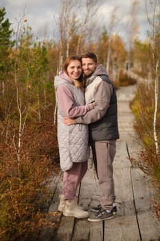 People in boots stand hugging on a wooden path in a swamp in Yelnya, Belarus.