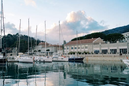 Sailing boats moored in a row on a pier with houses on the shore. High quality photo