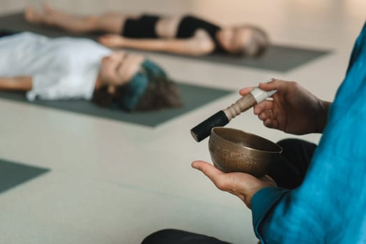 Children relax lying down to the sounds of a Tibetan bowl in the fitness room. Children's yoga.