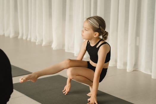 A child does yoga in the gym. Children's gymnastics.